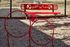 Inviting dog park area featuring vibrant red agility hoops and a 'Dogs N Play' bench, perfect for fun and exercise.