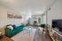 Chic living room with a vibrant green sofa, stylish decor, and abundant natural light creating a cozy ambiance.