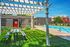 Inviting outdoor space with pergola, lush grass, picnic table, and a sparkling swimming pool, perfect for relaxation and leisure.
