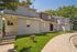 Charming two-story townhouse with beige and brown siding, nestled in a serene and lush green setting.