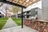 Charming apartment courtyard featuring lush greenery, modern balconies, and a cozy barbecue area under a pergola.
