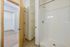 Bright and inviting bathroom with a modern shower and ample shelving, leading to a spacious walk-in closet.