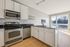Bright modern kitchen with sleek stainless steel appliances, elegant white cabinetry, and expansive windows offering scenic views.