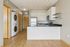 Modern kitchen with sleek appliances, elegant white cabinetry, and stylish wood flooring. Includes convenient in-unit washer and dryer.