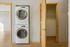 Modern apartment interior featuring a convenient in-unit stacked washer and dryer next to a spacious closet with wooden doors, complemented by sleek hardwood flooring.
