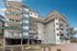 Contemporary apartment building showcasing multiple balconies, modern design, and secure parking under a clear blue sky.