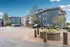 Charming residential complex with modern architecture, surrounded by lush greenery and ample parking space under a clear blue sky.