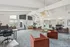 Modern, spacious office lounge with stylish red chairs, chic lighting, and large windows offering natural light.