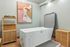 Modern bathroom featuring a sleek white freestanding tub, artistic wall painting, and stylish wooden storage, creating a serene spa-like retreat.