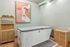 Modern home spa room featuring a stylish soaking tub, artistic wall decor, and wooden cabinets for elegant storage.
