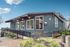 Modern leasing center with stylish architecture, lush landscaping, and inviting entrance under a clear blue sky.