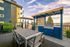 Charming outdoor patio with modern grill station and elegant dining set, perfect for entertaining against a scenic backdrop.