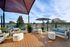 Chic outdoor lounge with modern furniture and stunning views, featuring stylish shade sails and lush greenery.