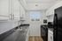 Bright, modern kitchen with sleek countertops, white cabinetry, and a large window offering natural light.