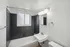 Bright and modern bathroom featuring elegant black tiles, a sleek white sink, and a large frosted window for natural light.