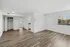Bright, spacious apartment with elegant hardwood floors, large window for natural light, and pristine white walls.