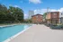 Inviting outdoor pool area with modern lounge chairs and lush landscaping, perfect for relaxation under a clear blue sky.