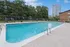Inviting outdoor swimming pool with lounge chairs, surrounded by lush greenery and a modern cityscape backdrop.