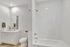 Bright, modern bathroom with elegant white tiles, sleek fixtures, and fresh floral accents.