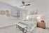 Bright and cozy bedroom featuring a modern ceiling fan, elegant artwork, and a plush bed with soft linens.