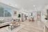Bright and modern open-concept living space with sleek kitchen, cozy seating area, and stylish dining table in an elegant apartment.