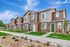 Charming row of modern townhouses with brown siding, surrounded by landscaped gardens and a clear blue sky.