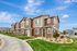 Charming townhouse community with modern architecture, lush landscaping, and inviting pathways under a bright blue sky.