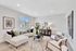 Elegant living room with contemporary decor, featuring a chic white sectional, stylish armchairs, modern art, and large windows inviting natural light.