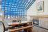 Elegant dining area with a vaulted glass ceiling, featuring a cozy fireplace and stylish wooden table set.