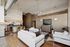 Chic open-concept living room with modern white sofas, stylish pendant lighting, and a sleek kitchen with bar seating.
