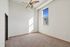 Bright, airy room featuring plush carpeting, high ceiling, and a large window with cityscape views, perfect for a cozy bedroom or office space.
