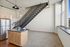 Modern urban loft with sleek metal staircase, large window for natural light, and a stylish kitchen island with stainless steel refrigerator.