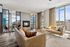 Bright and modern living room with plush leather sofas, cozy fireplace, and floor-to-ceiling windows offering stunning views.