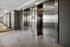 Modern residential elevator lobby with sleek metallic doors and a well-lit hallway featuring stylish floor tiles.