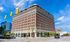 Impressive brick building with classic architectural details under a vibrant blue sky, ideal for modern urban living and business opportunities.