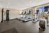 Modern fitness center with panoramic windows featuring treadmills, elliptical machines, and a multi-use weight station.