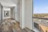 Bright and elegant apartment hallway with modern carpeting, large windows offering scenic city views, and ample natural light.