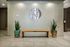 Elegant lobby entrance featuring a minimalist wooden bench, modern wall art, and stylish potted plants adding a touch of greenery.