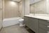 Modern bathroom with elegant beige tiles, sleek vanity, and pristine bathtub for a luxurious touch.