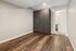 Modern bedroom with elegant wood flooring, sleek dark wood wardrobe, and soft neutral wall tones, featuring recessed lighting for a sophisticated ambiance.