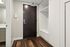 Elegant apartment entryway featuring a sleek dark wood door, modern laminate flooring, and built-in white storage cabinets.