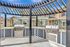 Charming outdoor space with two modern grills under a stylish pergola, overlooking elegant townhouses.