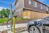 Modern townhouse with electric vehicle charging station, showcasing eco-friendly living and stylish brown siding exterior.