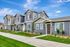 Charming townhouse exterior with modern blue siding and well-maintained landscaping under a clear blue sky.