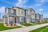 Charming two-story townhouse with modern exterior, nestled in a serene suburban neighborhood, featuring landscaped gardens and a welcoming pathway.
