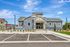 Charming modern building with sleek blue-gray siding, front porch, and inviting entrance, surrounded by well-maintained landscaping and ample parking space.