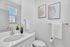 Contemporary bathroom with sleek white vanity, elegant decor, and bright natural lighting.