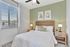 Inviting bedroom with a stylish woven headboard, serene green accent wall, and cozy ambient lighting from sleek side table lamps.