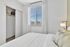 Bright and inviting bedroom with plush pillows, ample closet space, and a sunlit window offering a charming neighborhood view.