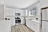 Bright and modern kitchen with sleek white cabinetry, stainless steel appliances, and elegant hardwood flooring.